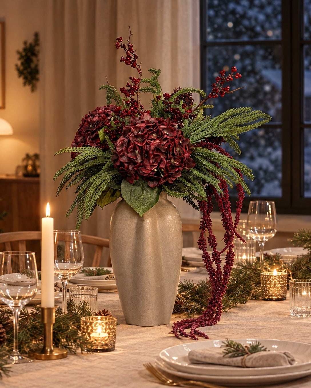 Julebuket i bordeaux og gran i en beige keramikvase midt på et dækket julebord med levende lys